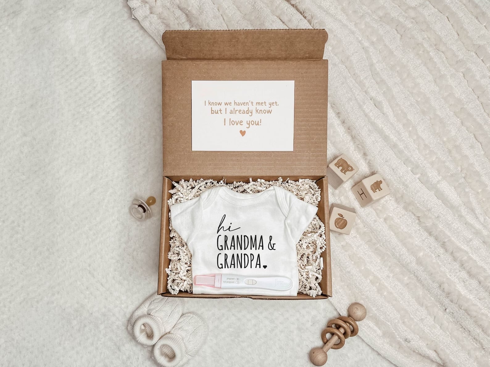 Pregnancy announcement gift box for parents with baby onesie and pregnancy test.