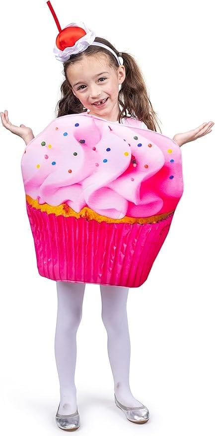 Smiling girl in a pink cupcake Halloween costume with printed frosting, colorful sprinkles, and a cherry headband — fun and sweet outfit idea for a baking or dessert-themed family costume