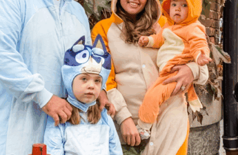 Family of four dressed in Bluey Halloween costumes — dad as Bandit, mom as Chilli, older daughter as Bluey, and baby as Bingo.