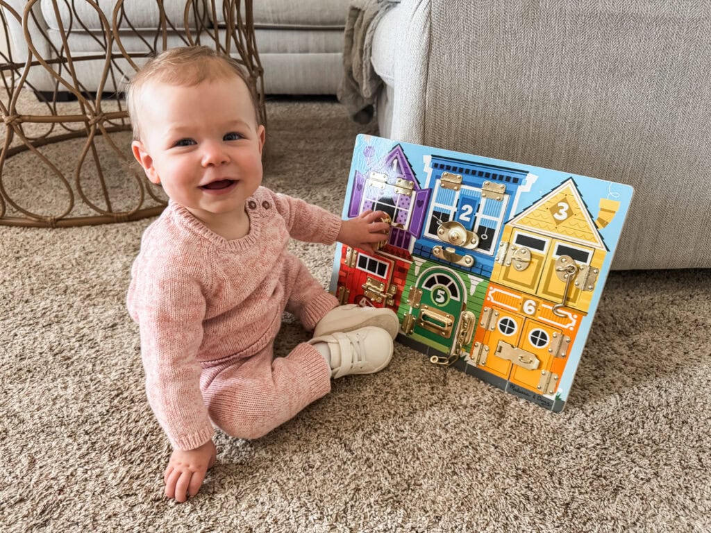 Toddler playing with Melissa and Doug wooden latches board sensory toy for toddlers.
