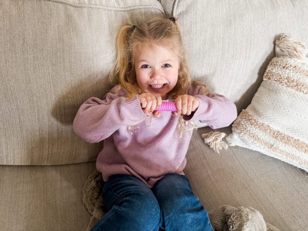 Girl playing with pop tube sensory toy for toddlers.