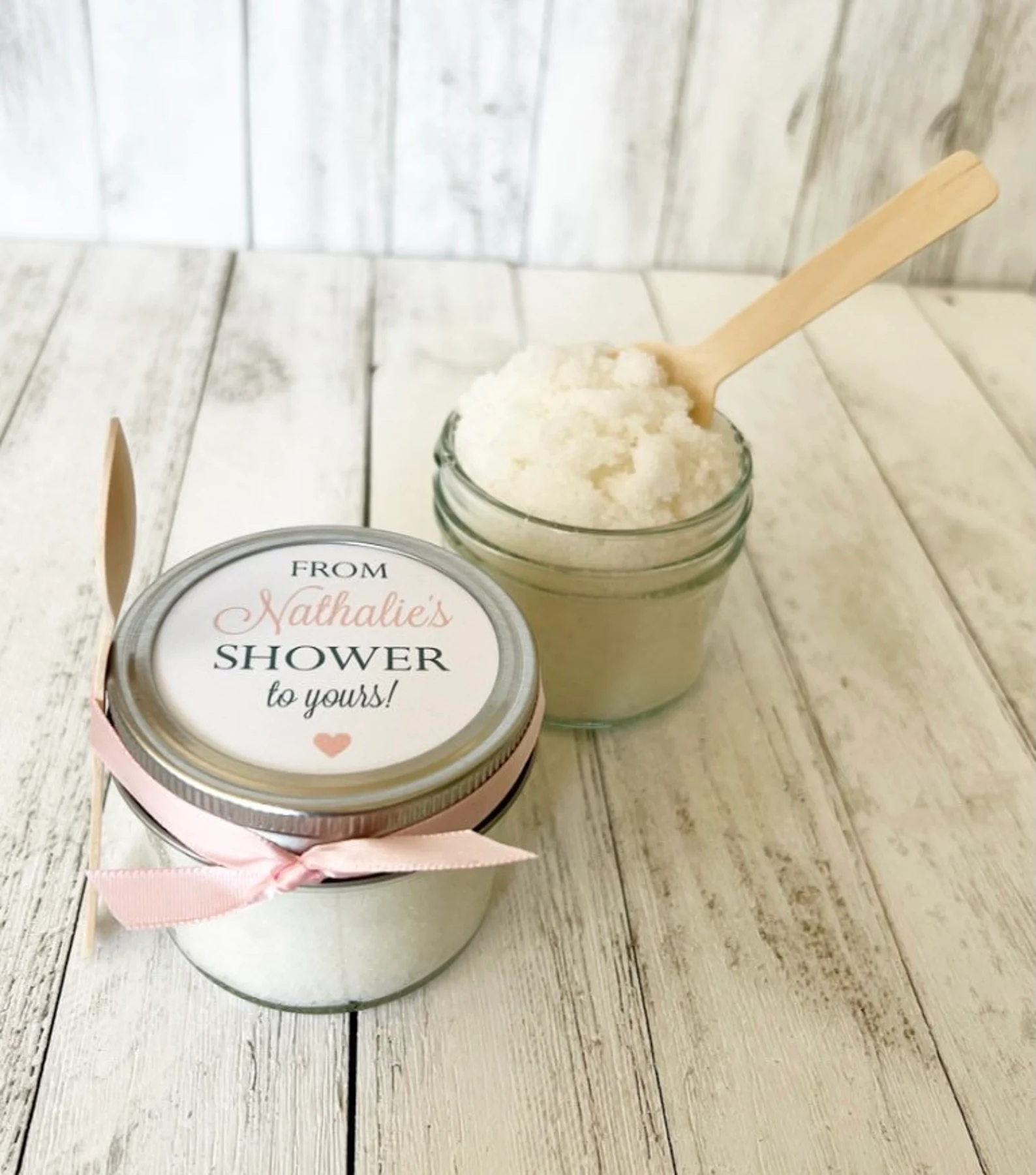 A jar of sugar scrub with label reading “from Nathalie’s shower to your” for a baby shower party favor.