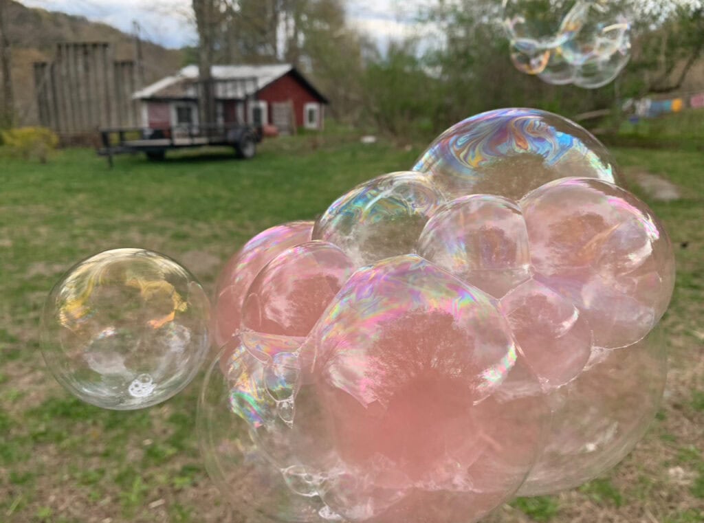 Bubbles filled with pink smoke at an outdoor summer gender reveal.