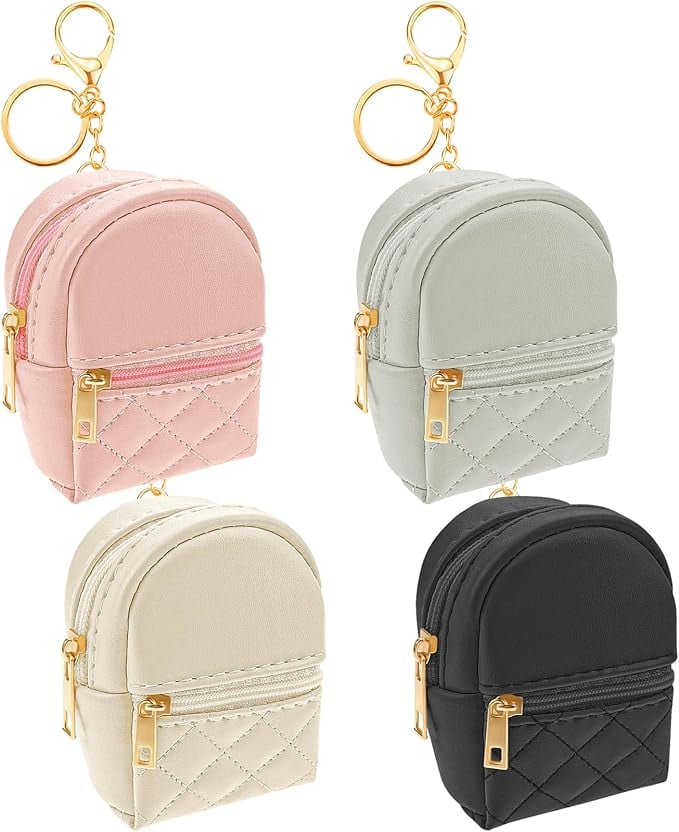Set of four mini quilted backpack keychains in pink, gray, cream, and black with gold zippers and key rings. Stylish and practical baby shower party favors or gifts for guests.