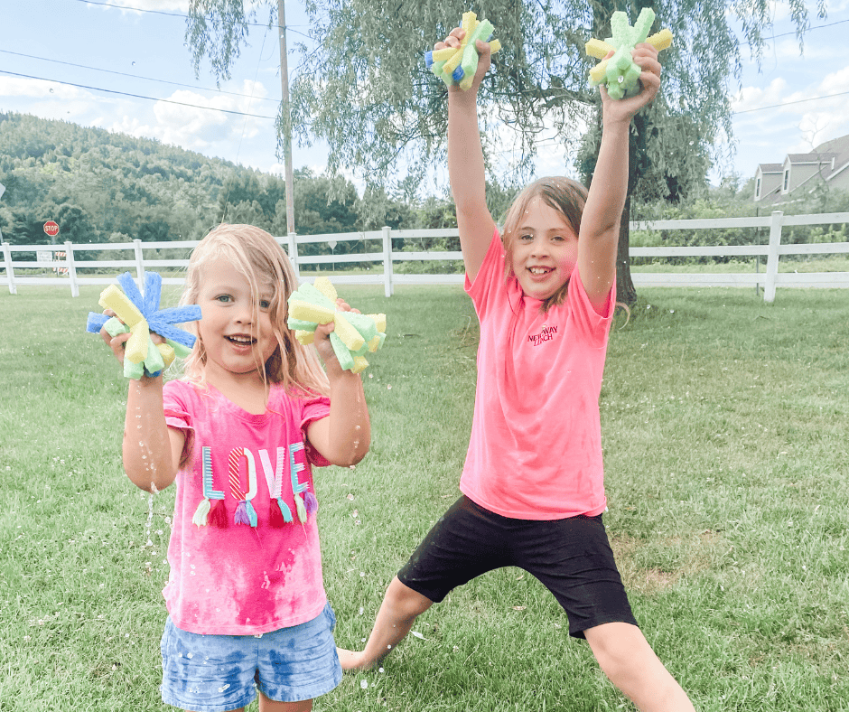 Two kids holding up soaked diy sponge water balloons during the summer.