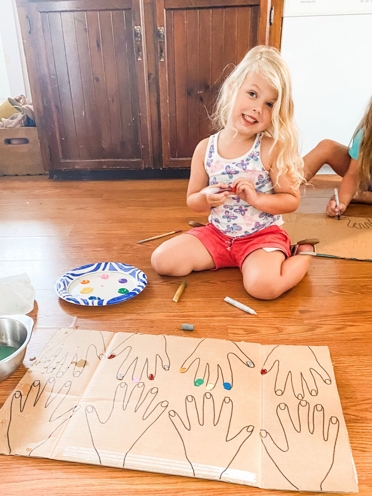 Girls painting nails on cardboard cutouts or pretending to do each other’s nails