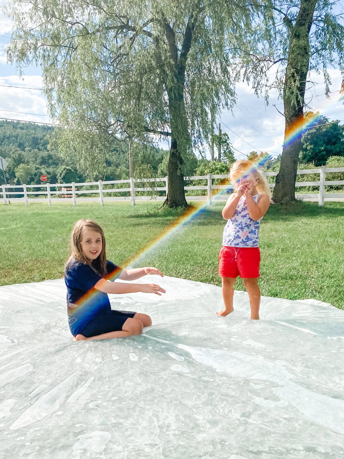 Children playing on a homemade water blob on the lawn