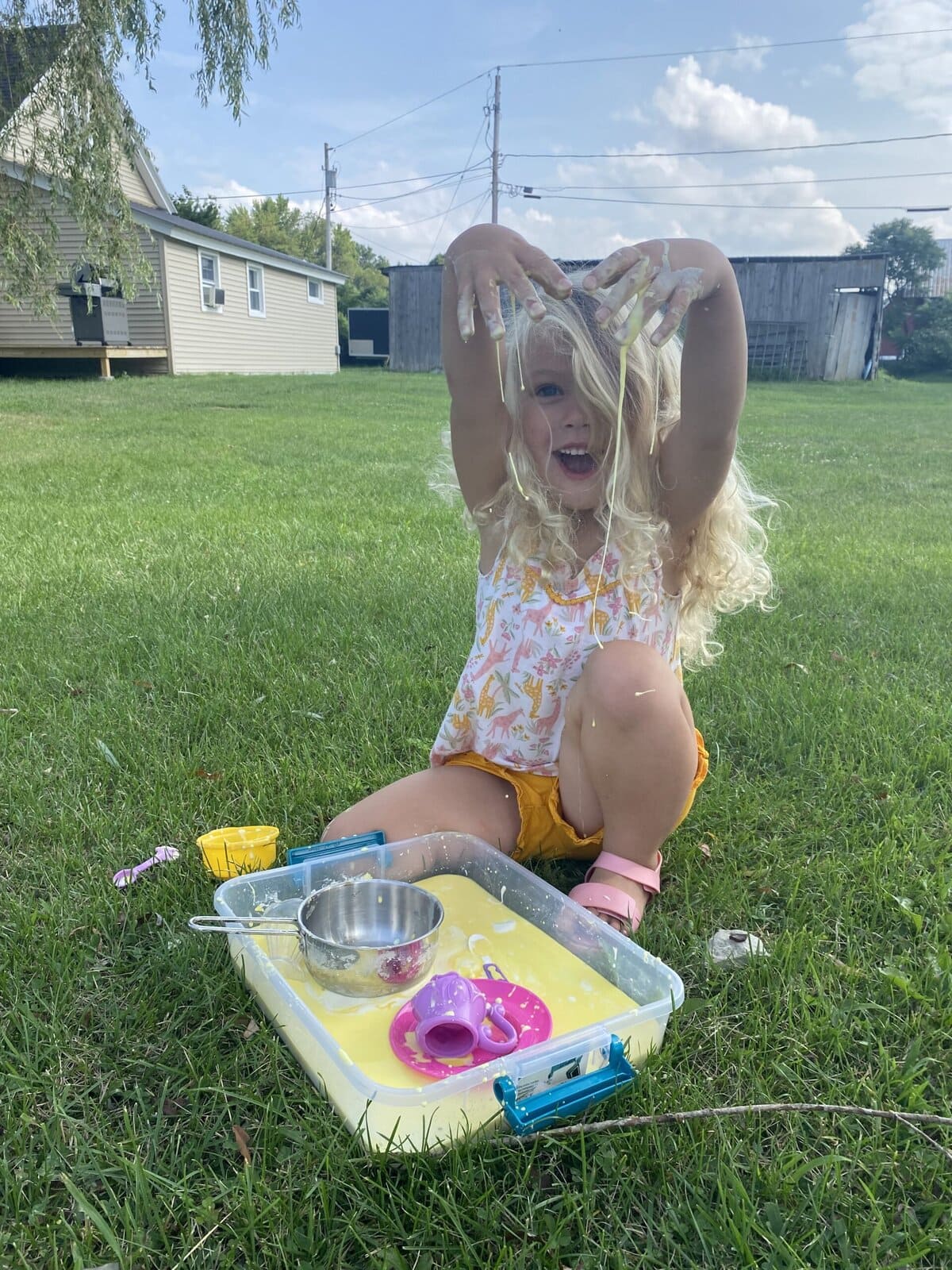 Child’s hands squishing and lifting gooey homemade oobleck in a bowl