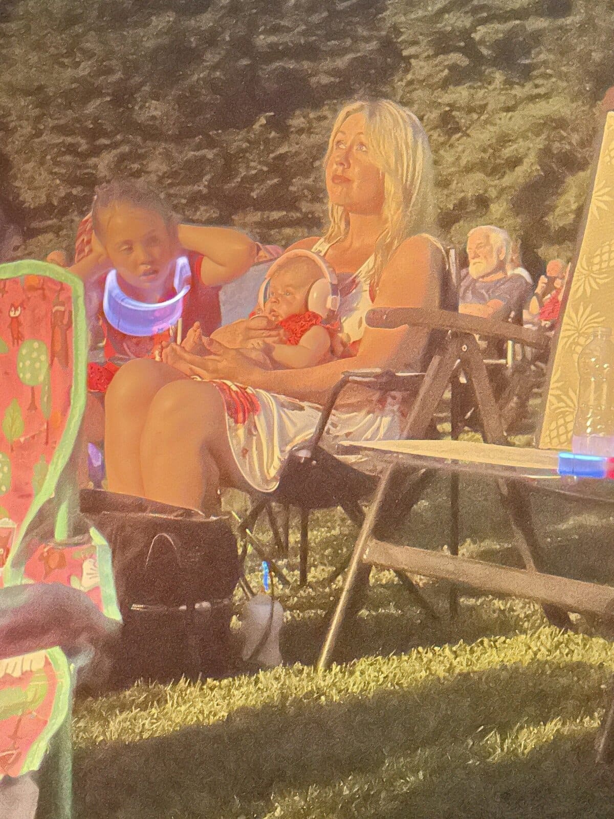 Kids sitting in chairs watching fireworks light up the night sky