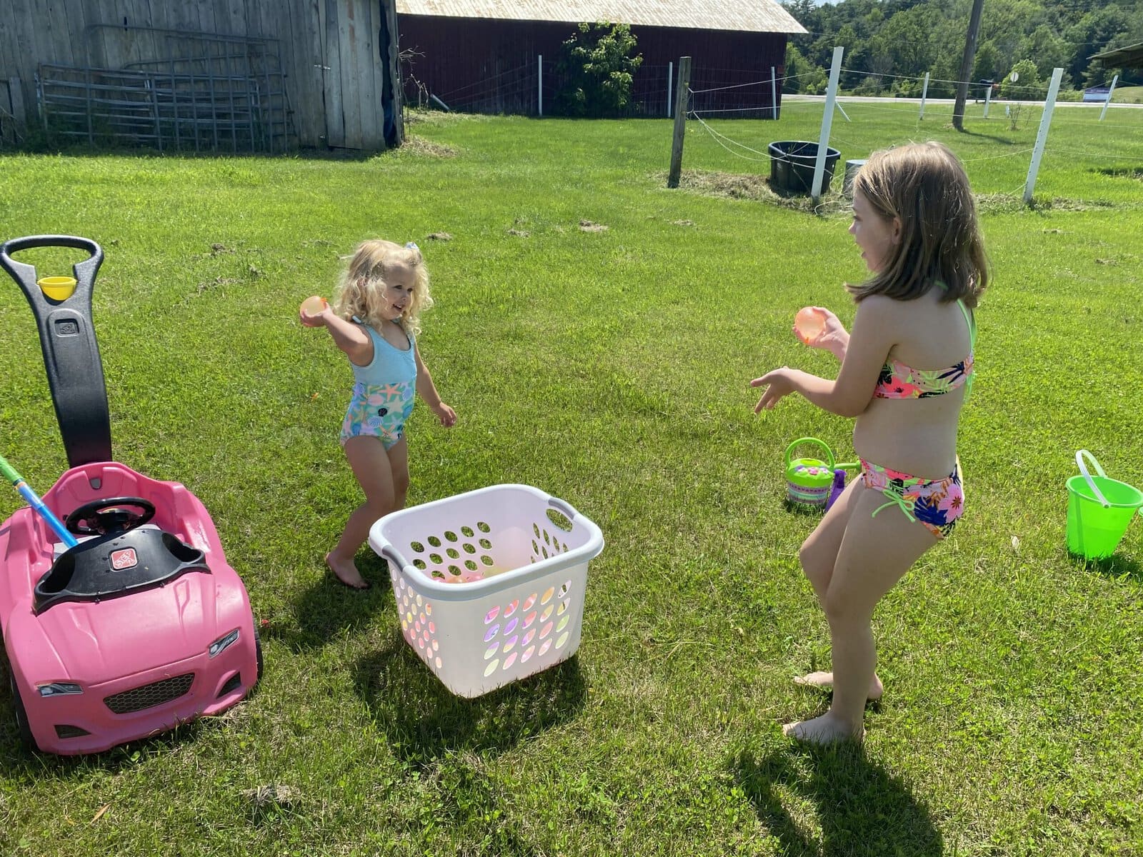 Kids holding water balloons mid-battle, smiles and soaked clothes in a backyard