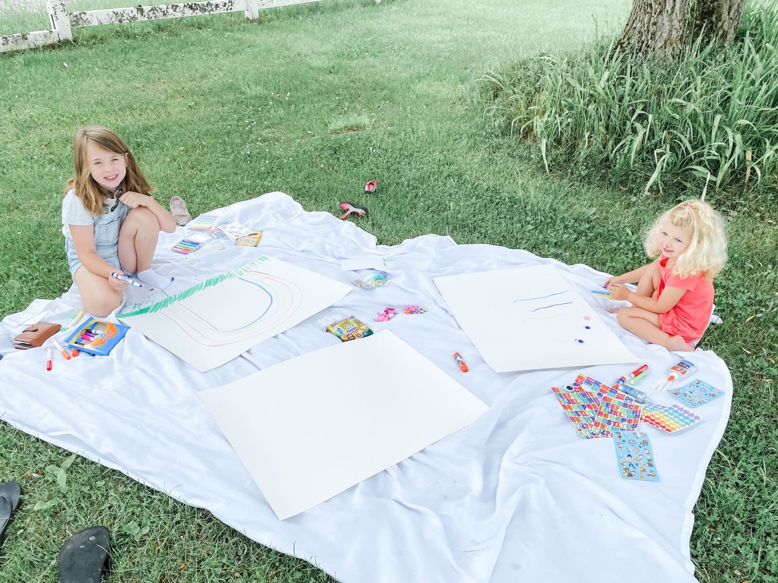 Fun summer activity where kids have outdoor arts and craft time on a blanket in the grass.