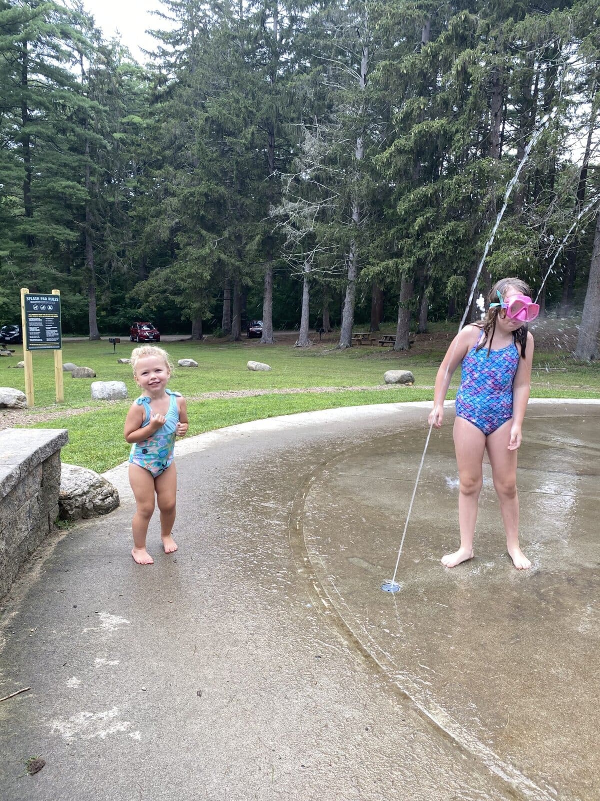 Child running through water sprayers and fountains at a public splash pad