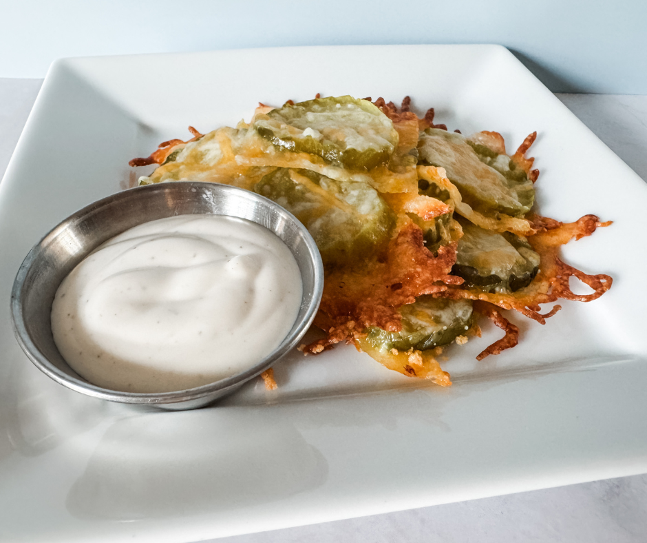 Baked pickle chips with melted cheese served with ranch dip.