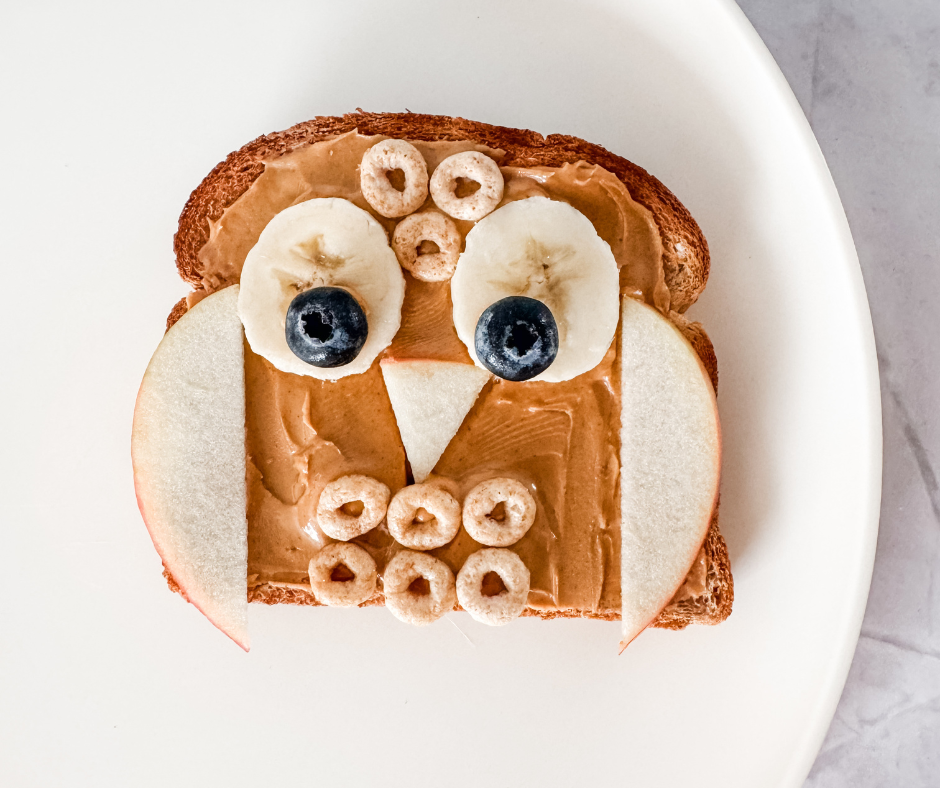 Owl toast made with peanut butter, bananas, blueberries, apples, and cereal — a cute and healthy snack idea for kids.