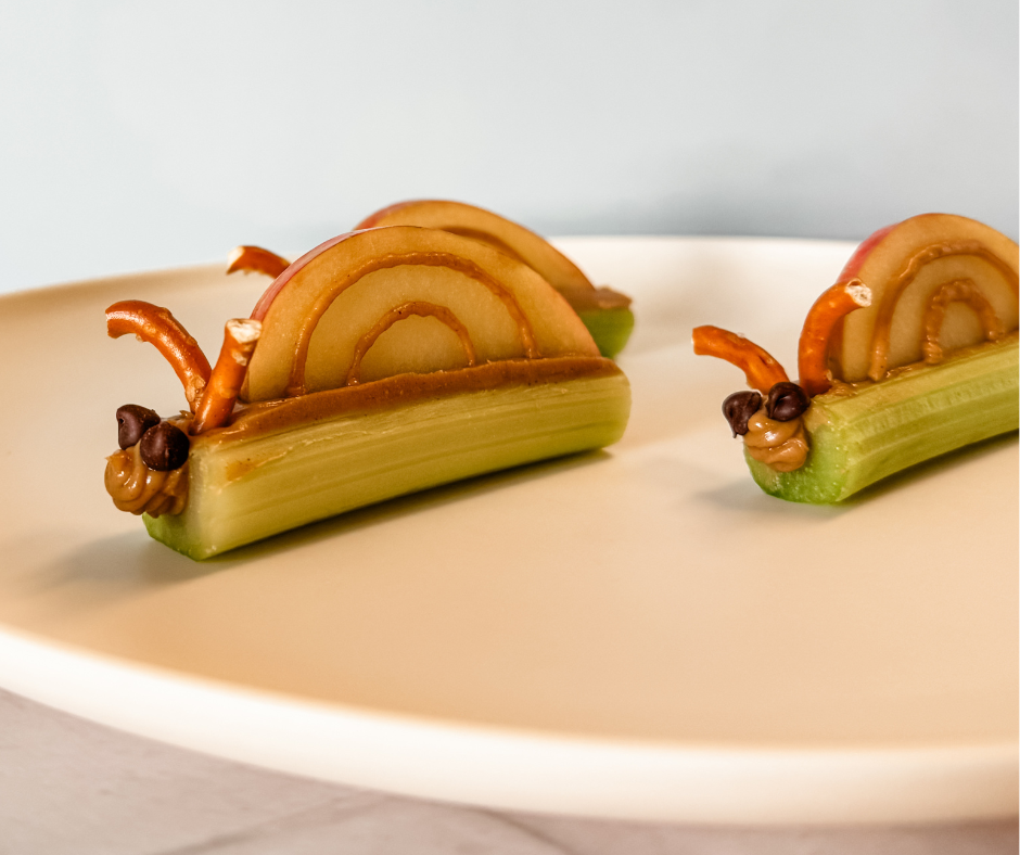 Snail snacks made with celery, peanut butter, apple slices, pretzels, and mini chocolate chips. A fun and healthy snack idea for kids.