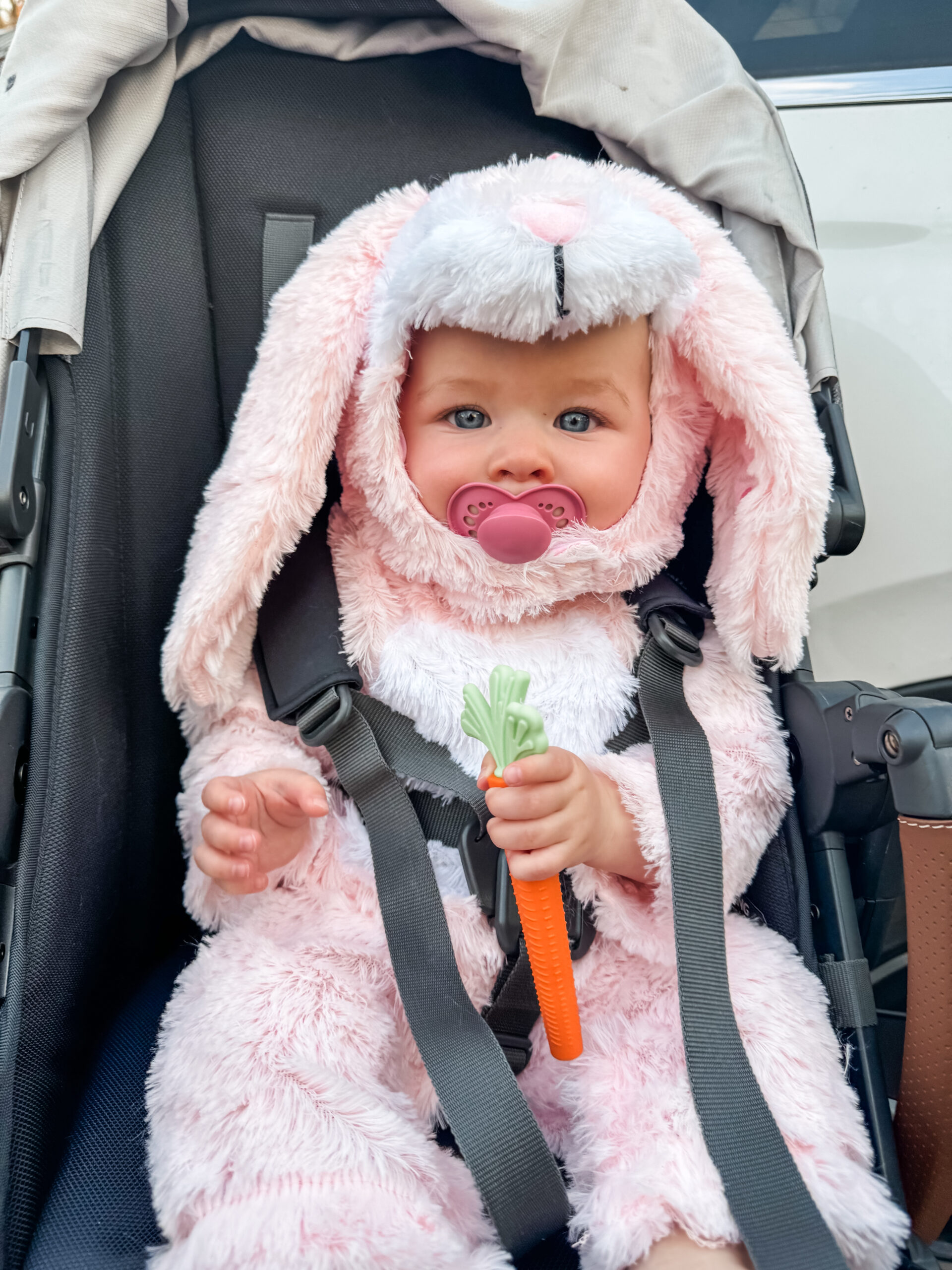 Baby girl in bunny Halloween costume for girls holding a carrot teether toy