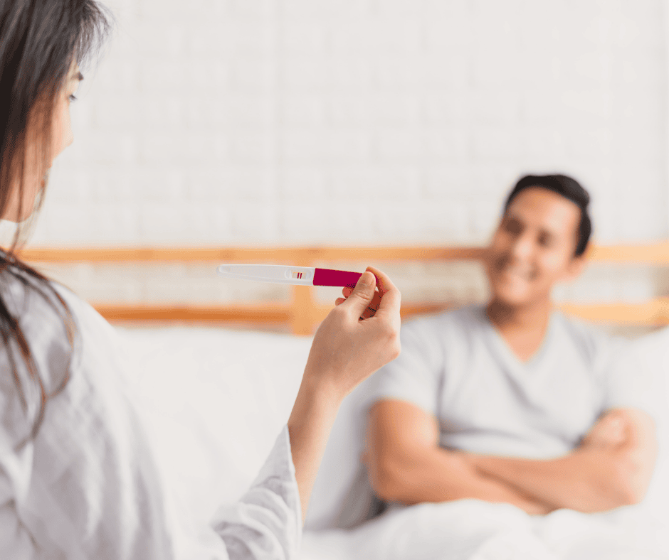 Women showing pregnancy test to husband as a pregnancy announcement.