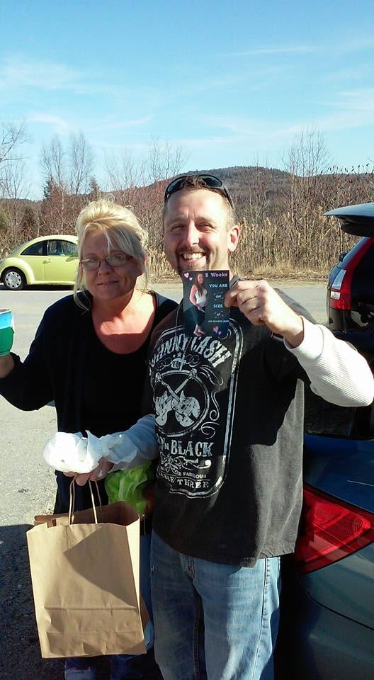 Proud grandparents to be hold up pregnancy announcement to parent photo.