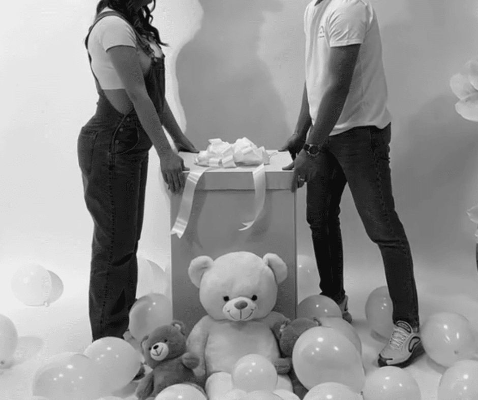 Black and white image shows pregnant couple about to open a box during their gender reveal party.