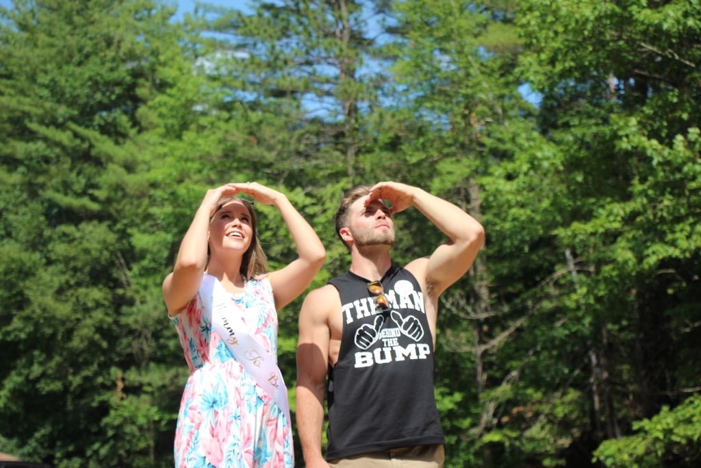 Eager pregnant couple looks at the sky during their gender reveal party.