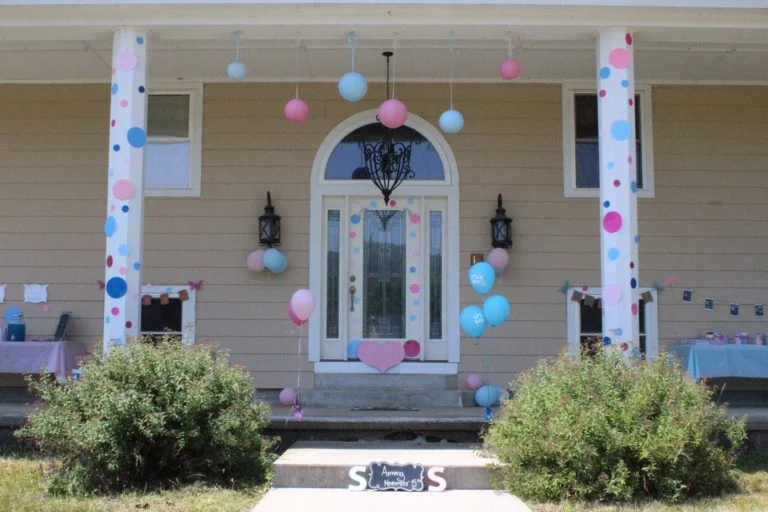 Front porch decorated with blue and pink gender reveal decorations.