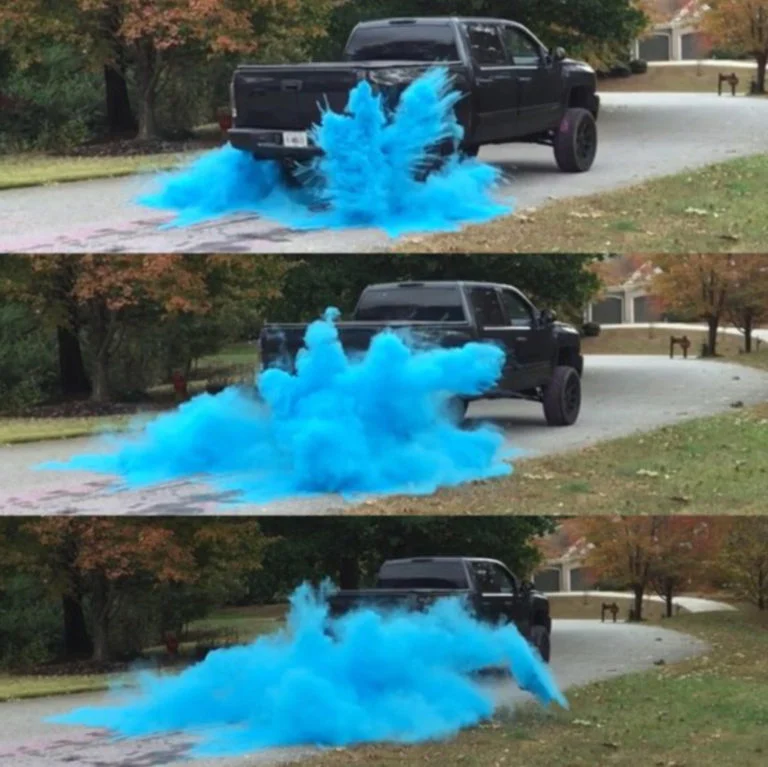 Black truck emitting blue smoke from its exhaust for a gender reveal party idea.