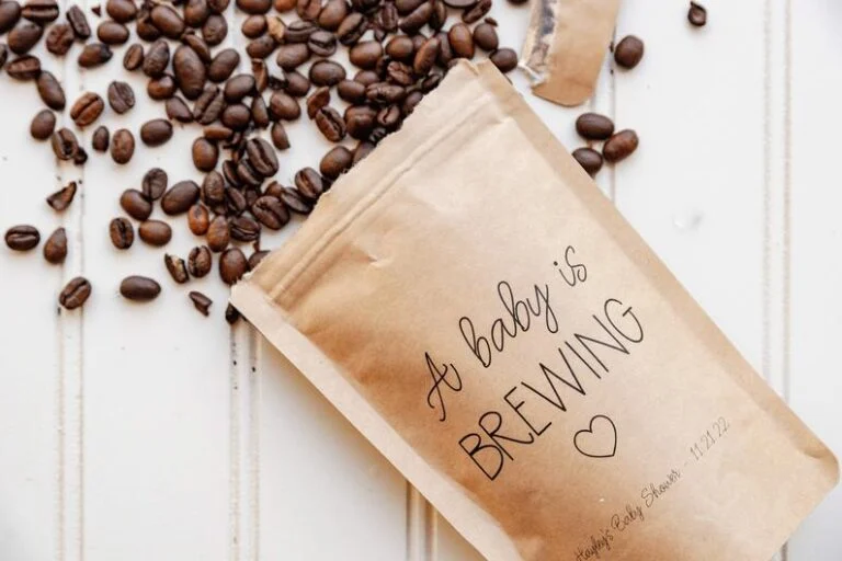 Coffee beans spilling out of a paper bag baby shower party favor that say a baby is brewing.