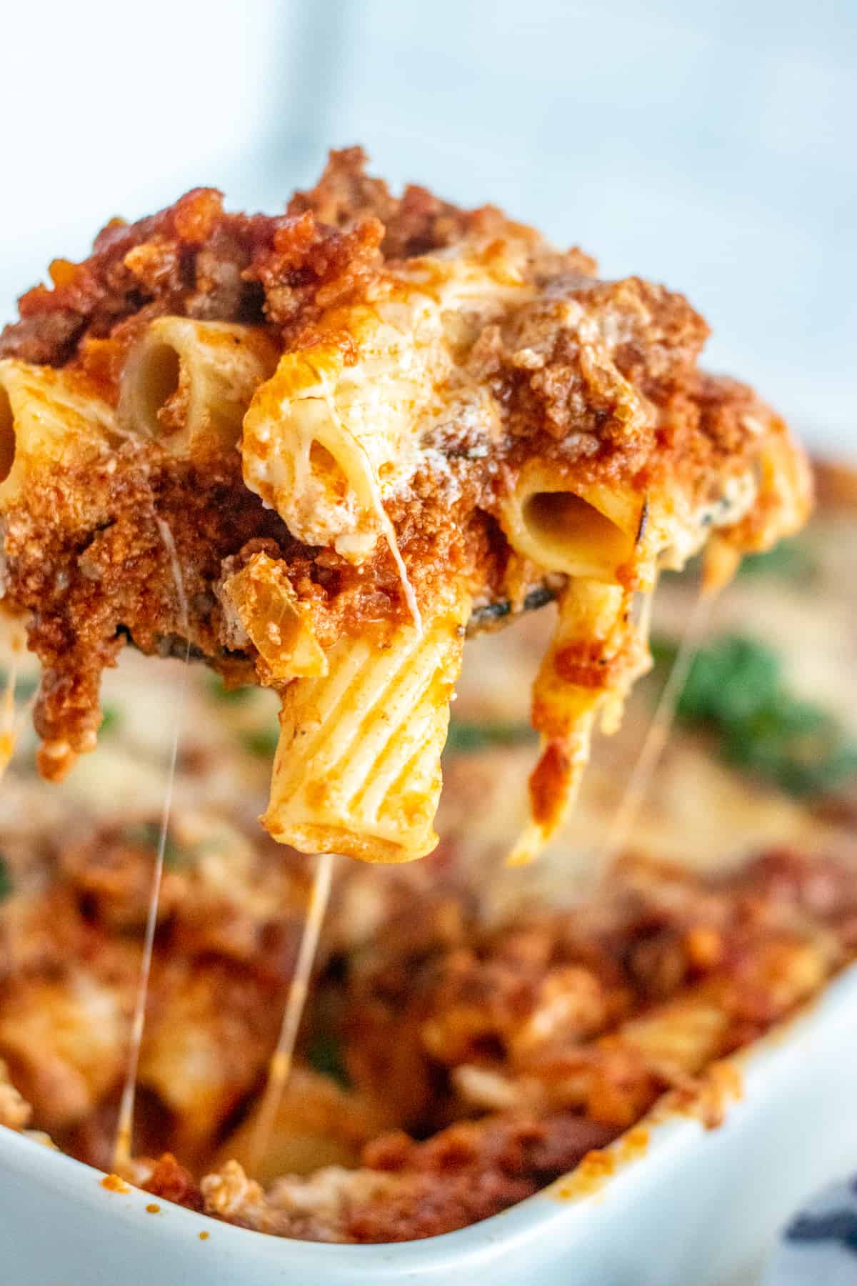 Postpartum freezer meal baked ziti with meat sauce and melted cheese being served from casserole dish