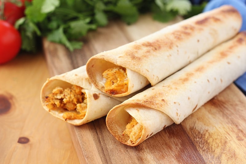 Postpartum freezer meal baked chicken taquitos rolled in tortillas on wooden cutting board