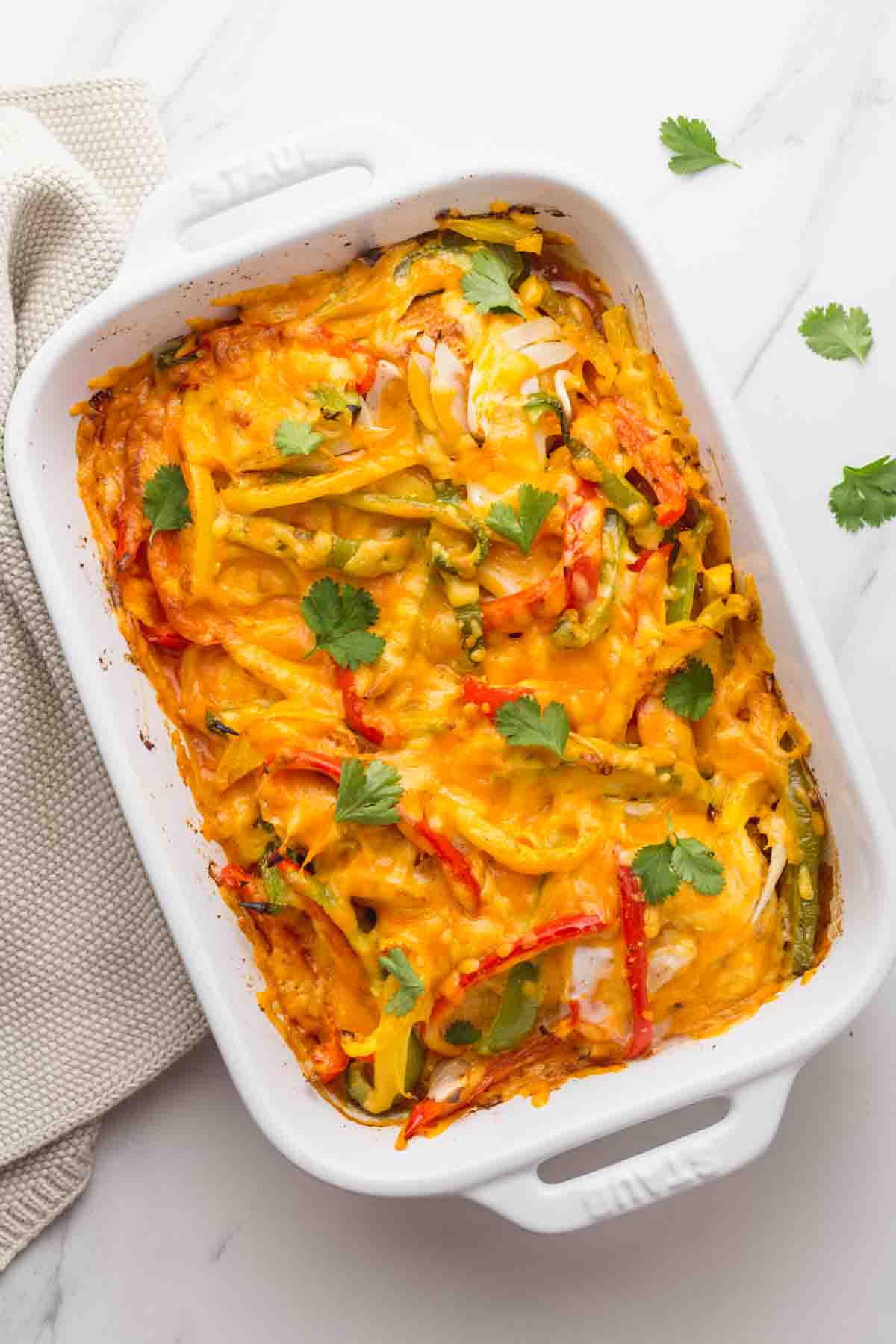 Chicken fajita casserole with peppers and melted cheese baked in white dish