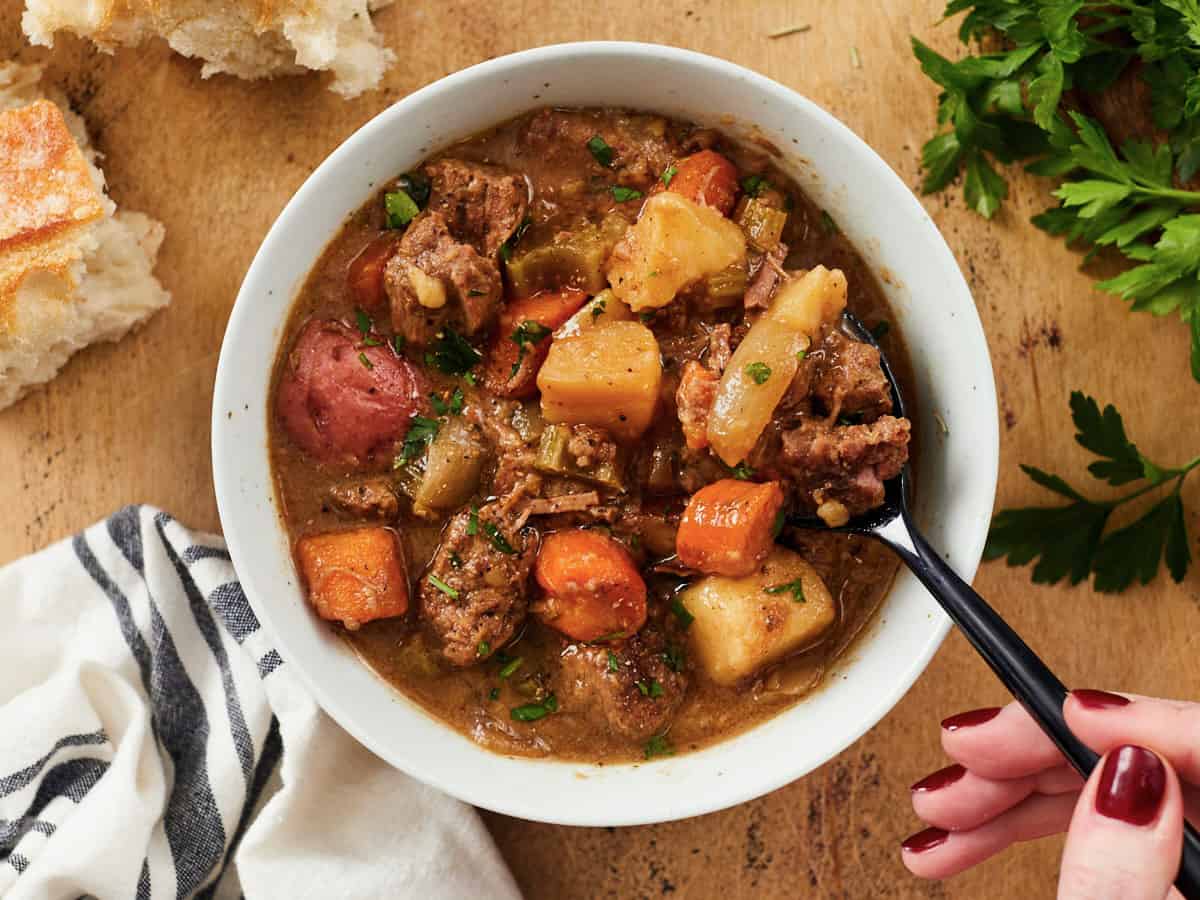 Slow cooker beef stew with potatoes carrots and chunks of beef in bowl.
