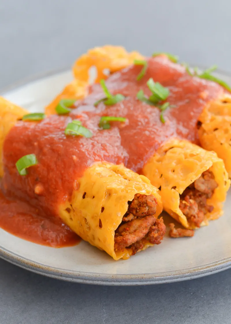 Low carb enchiladas with ground beef and melted cheese topped with red sauce on a plate, gestational diabetes dinner idea