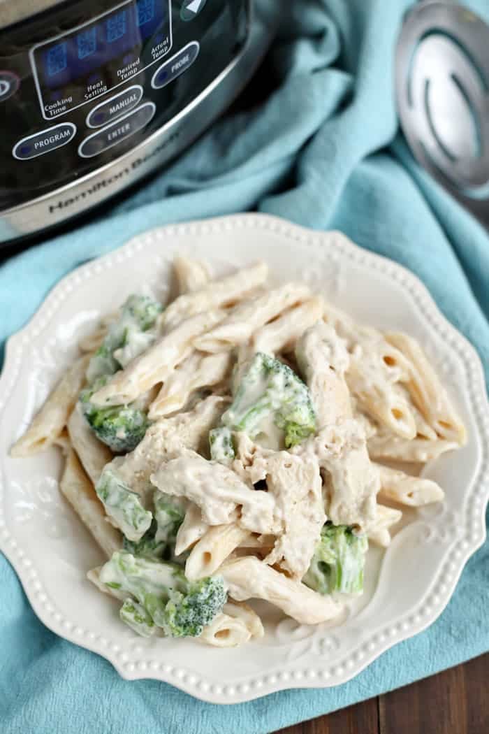 Crock-pot freezer meal chicken Alfredo with penne pasta, broccoli, and creamy Alfredo sauce served on a white plate.