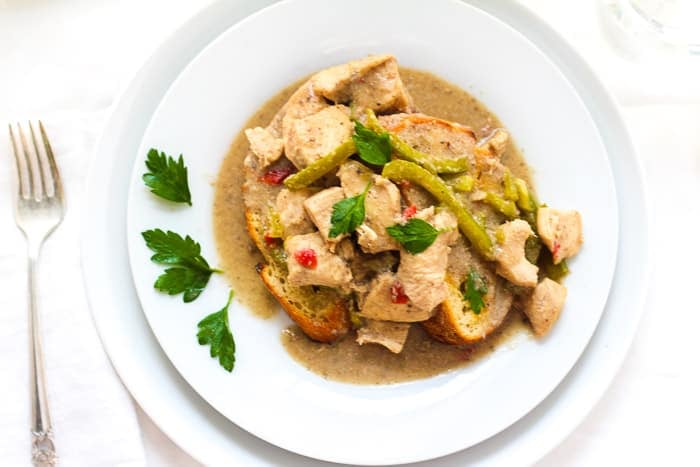 Slow cooker chicken à la king served over toasted bread and parsley garnish.