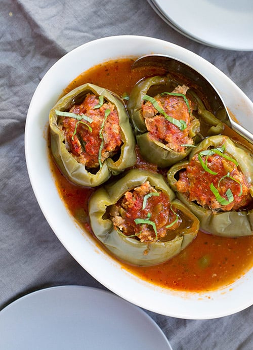 Slow cooker stuffed peppers filled with meat and sauce in a white serving dish.