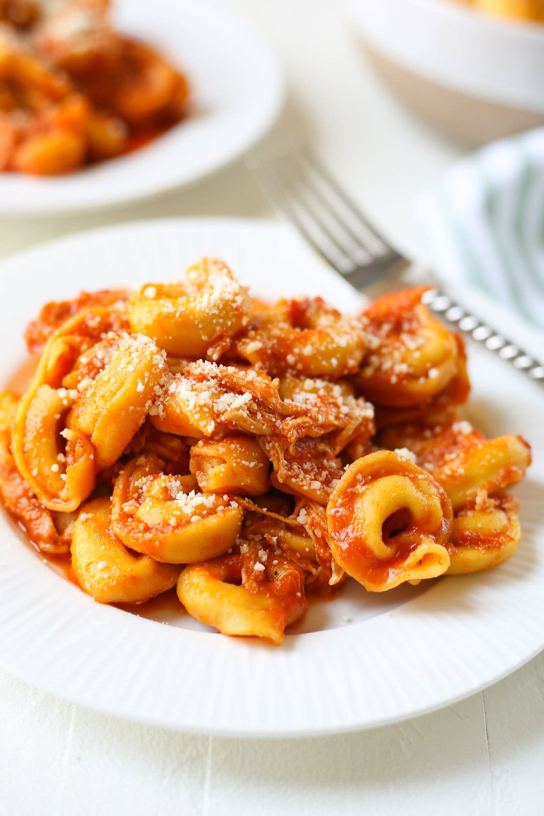 Slow cooker chicken Parmesan tortellini topped with marinara sauce and grated Parmesan cheese.