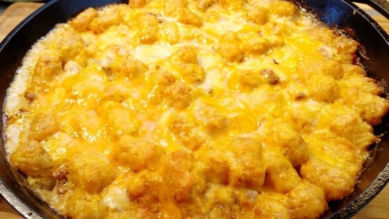 Slow cooker cheeseburger bacon ranch tater tot casserole topped with melted cheddar cheese and crispy tater tots.