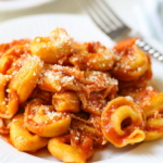 Crock-pot freezer meal for new moms consisting of tortellini chicken Parmesan on a white plate.