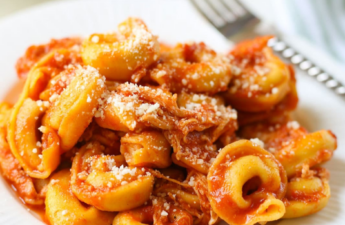 Crock-pot freezer meal for new moms consisting of tortellini chicken Parmesan on a white plate.