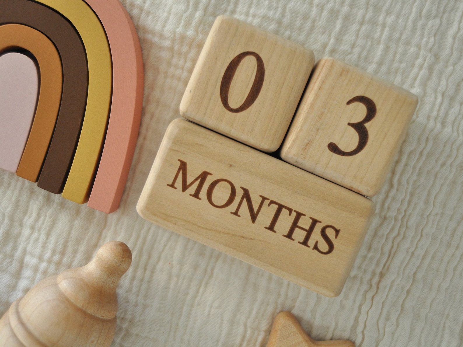 Baby monthly milestone blocks laying on a white muslin blanket.
