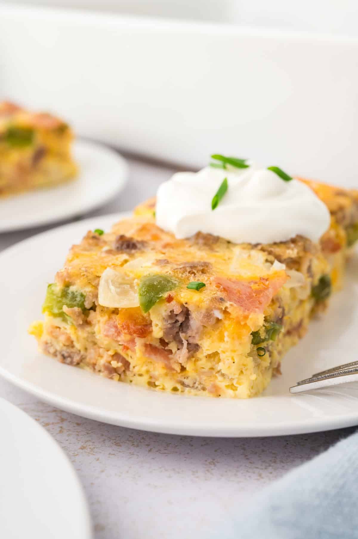 Easy gestational diabetes breakfast consisting of an egg casserole with sausage, cheese, bell peppers, onions, and tomatoes topped with sour cream and chives.