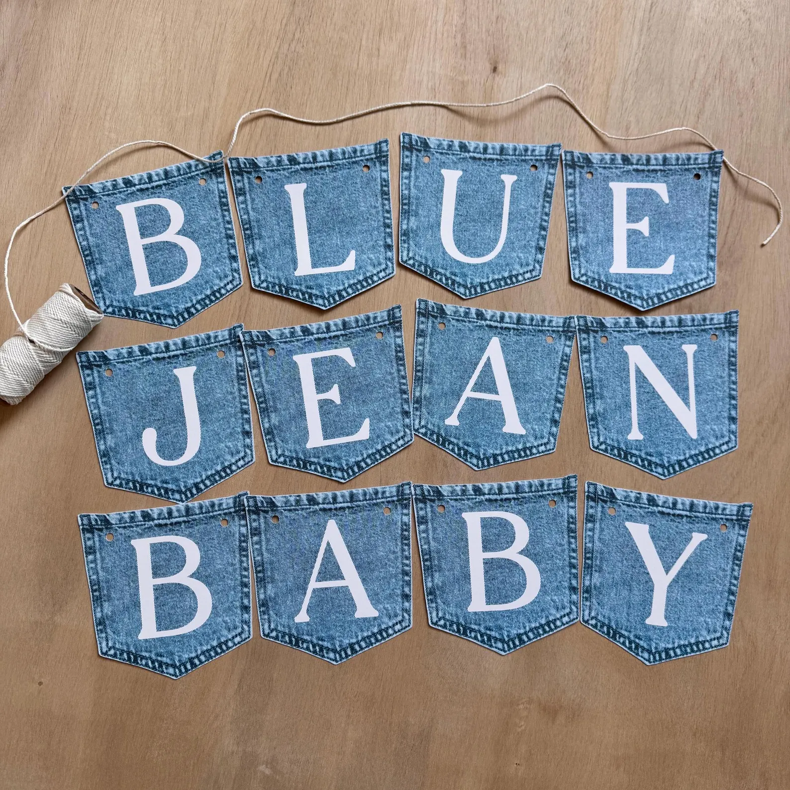 Blue Jean Baby banner made from denim jean pockets with white lettering and twine for a blue jean baby shower theme.