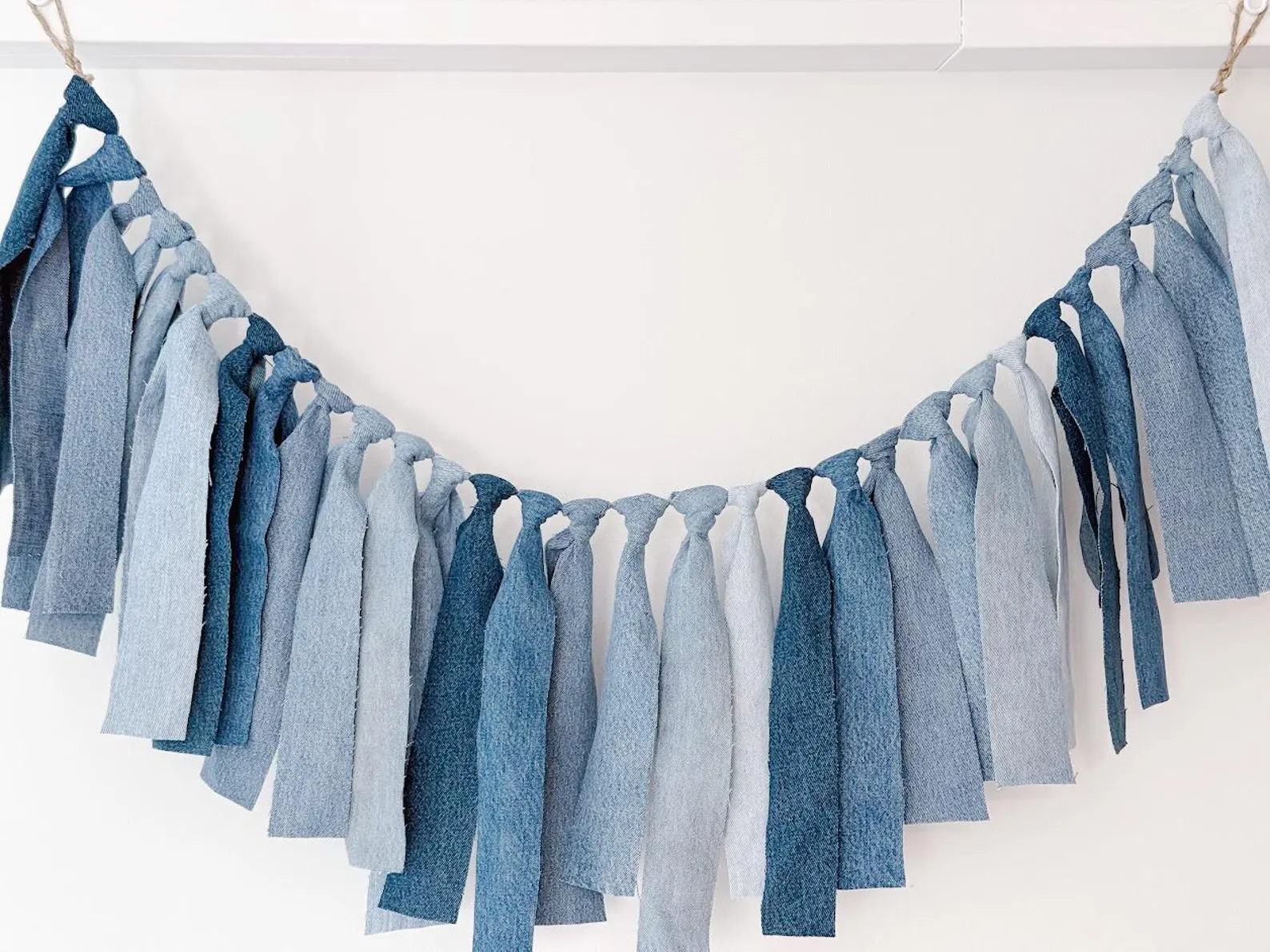 Garland made from strips of light and dark blue denim tied onto twine for a blue jean baby shower theme.