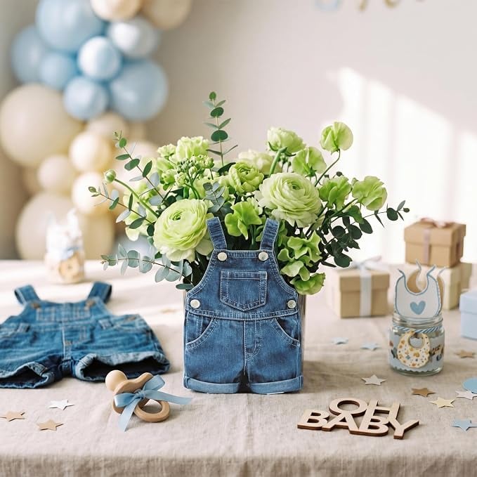 Baby denim overalls filled with green and white flowers on a decorated table for a blue jean baby shower theme.