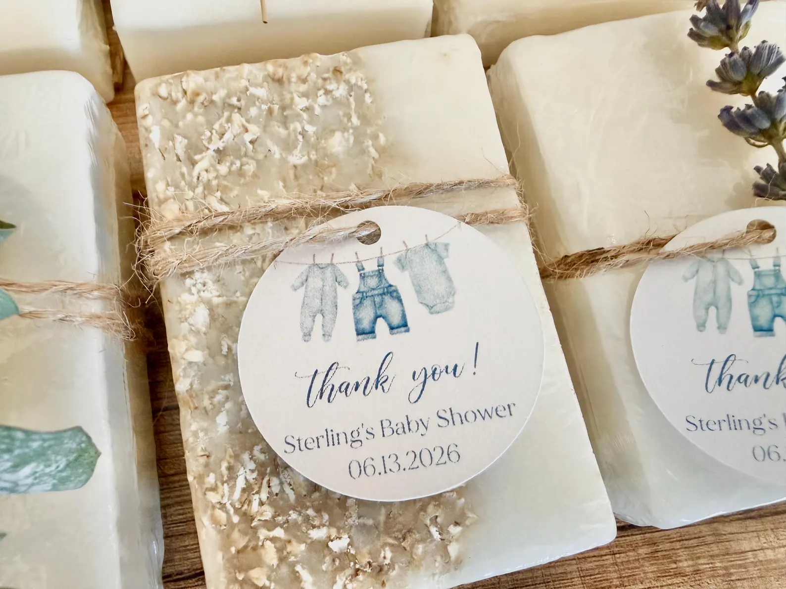 Handmade soap bars wrapped with twine and personalized tags featuring watercolor denim baby clothes for a blue jean baby shower theme.
