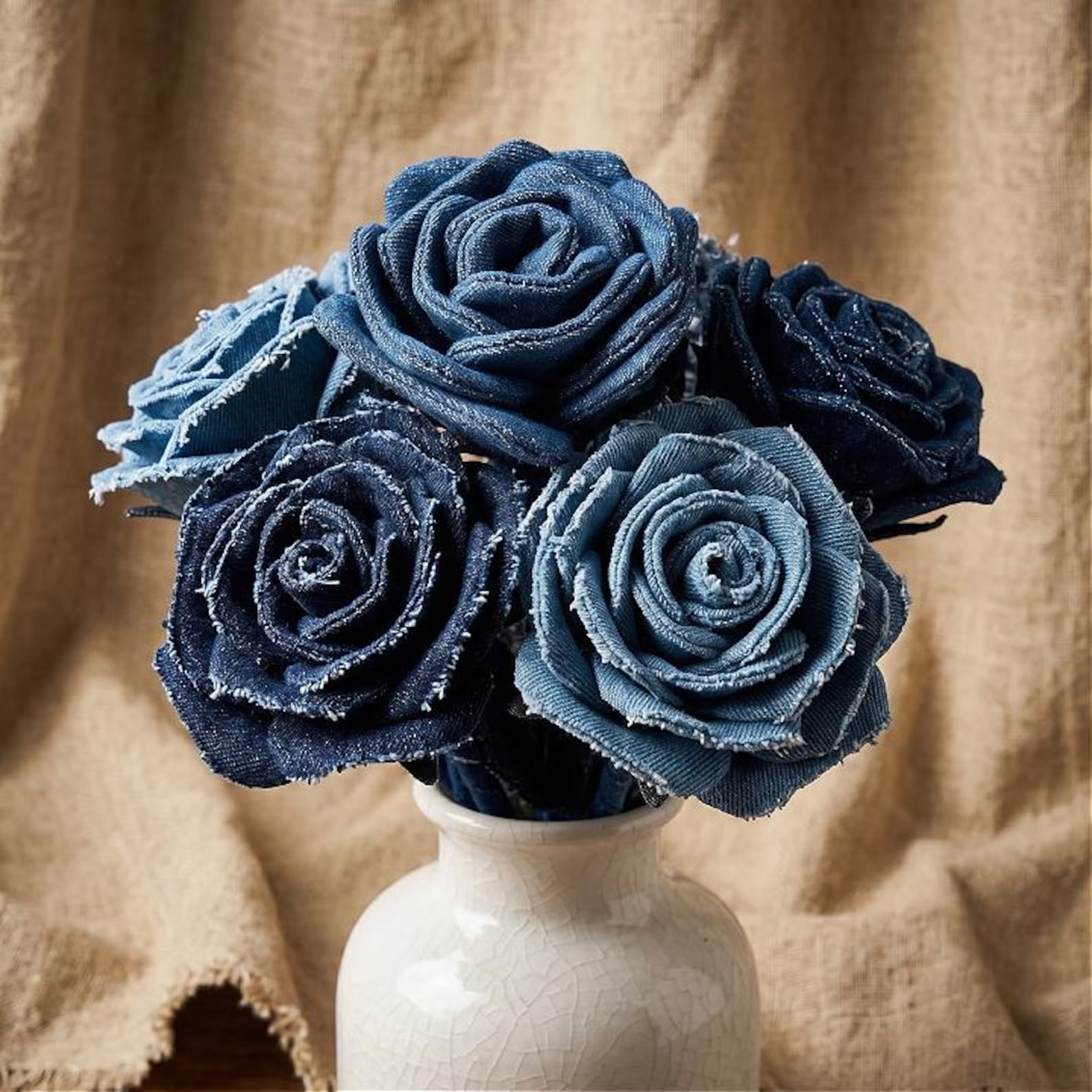 Handmade roses created from light and dark blue denim fabric arranged in a white vase for a blue jean baby shower theme.