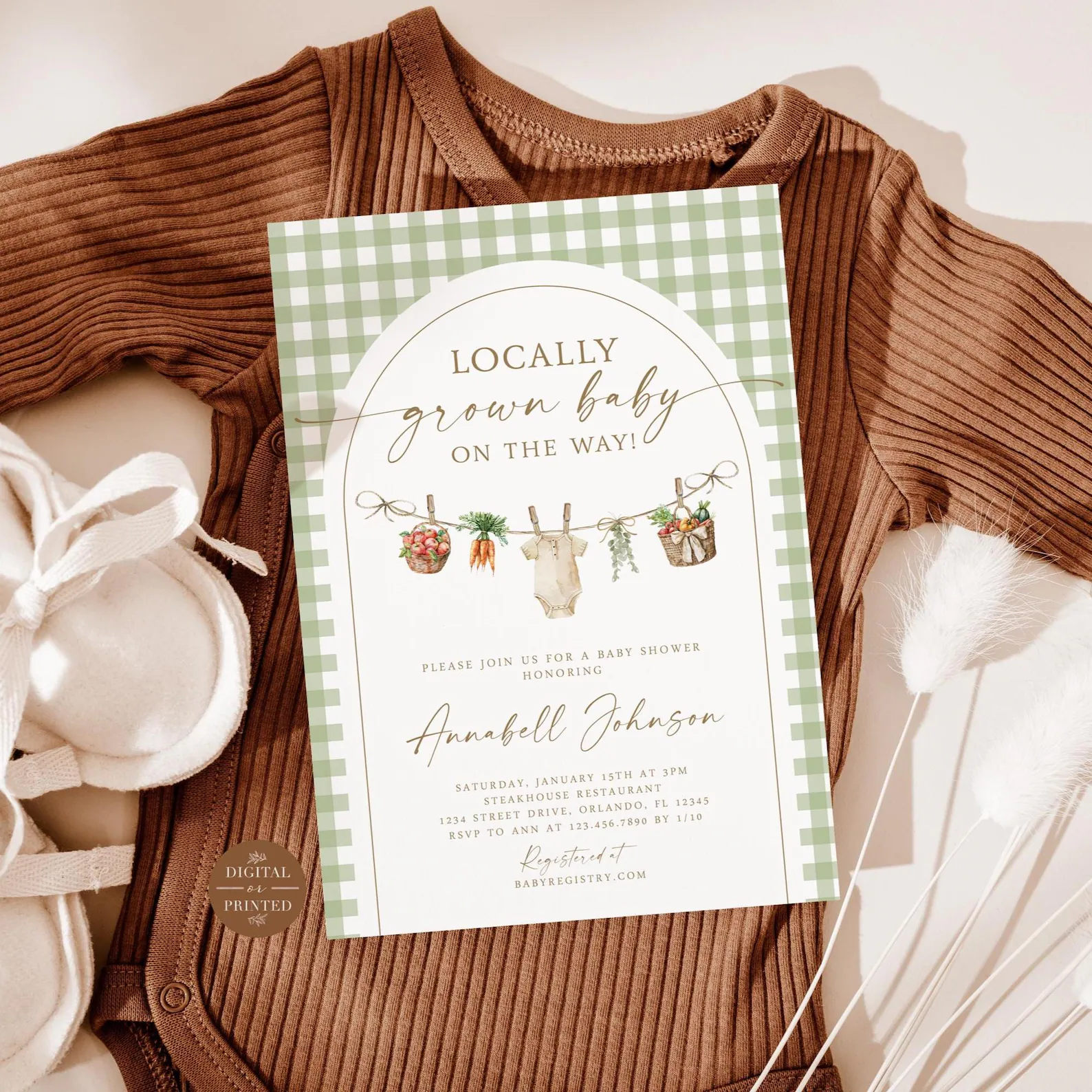 Locally grown baby shower invitation with sage green gingham, garden vegetables, greenery, and a baby onesie displayed over a brown ribbed baby outfit.