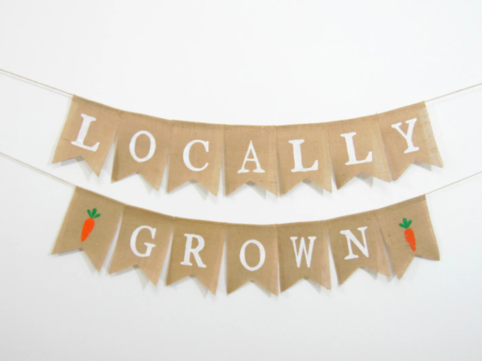 Locally grown baby shower banner made from rustic burlap pennants with white lettering and small orange carrot details.