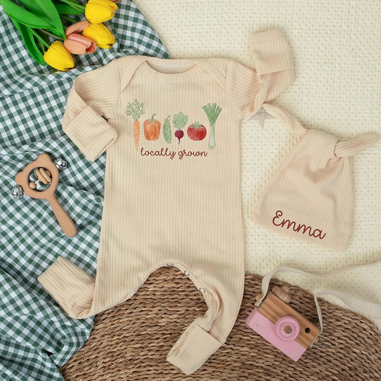 Locally grown baby shower gift featuring a neutral ribbed baby outfit decorated with colorful garden vegetables, paired with a personalized baby hat.
